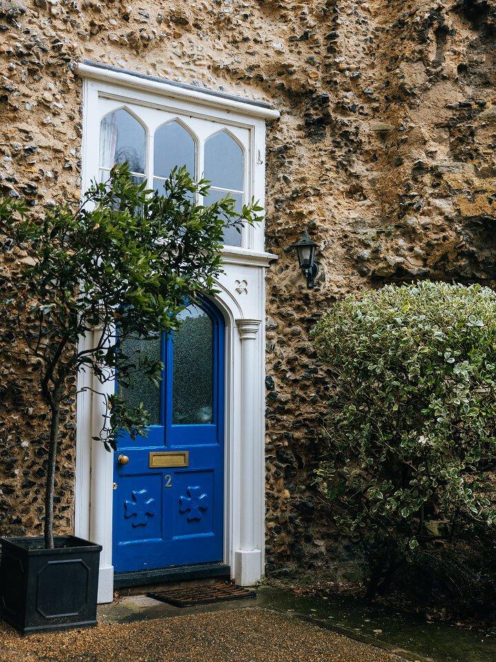 a blue door with a potted plant in front of a stone building